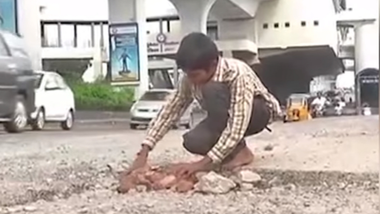 boy fill road potholes