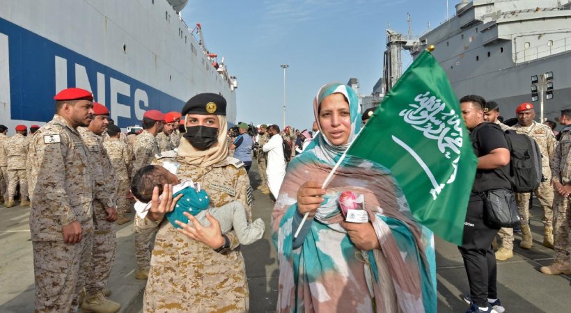 Members of the Saudi Arabian navy assist evacuees arriving at King Faisal naval base in Jeddah on 26 April 2023 (AFP)